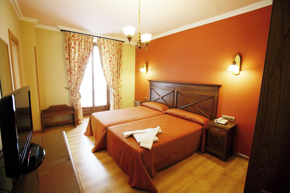 Una habitación de hotel con dos camas, televisión, escritorio y silla.