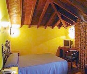 Quarto com uma cama, uma mesa com computador e uma cadeira.