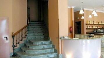 Una escalera conduce a un rellano donde se observa un área de cocina al fondo.
