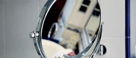 A bathroom with a round mirror mounted on a wall, a sink, and a towel rack.