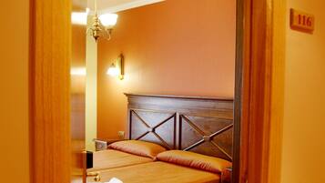 Ein Hotelzimmer mit Holz-Kopfteil, zwei Betten, einem Holzstuhl, einem Schreibtisch und einem Nachttisch.