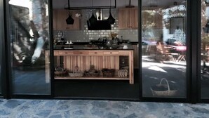A modern kitchen with a black countertop, wooden cabinets, and a hanging light fixture. - Misafir Evi Hotel (Fethiye)
