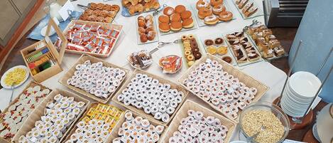 A buffet table with various food items including pastries, cookies, and condiments.