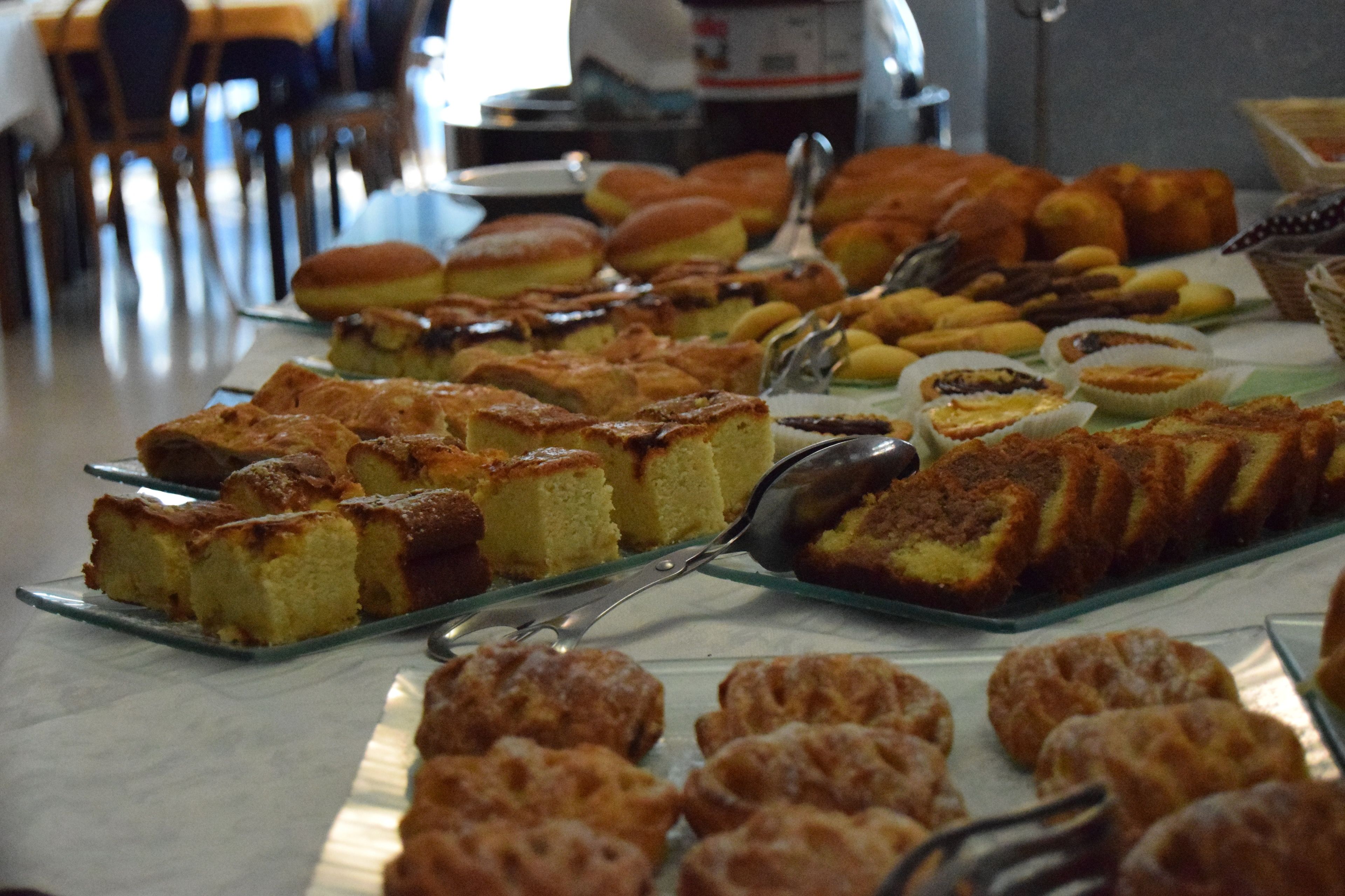 A buffet with various baked goods including cakes, pastries, and bread.