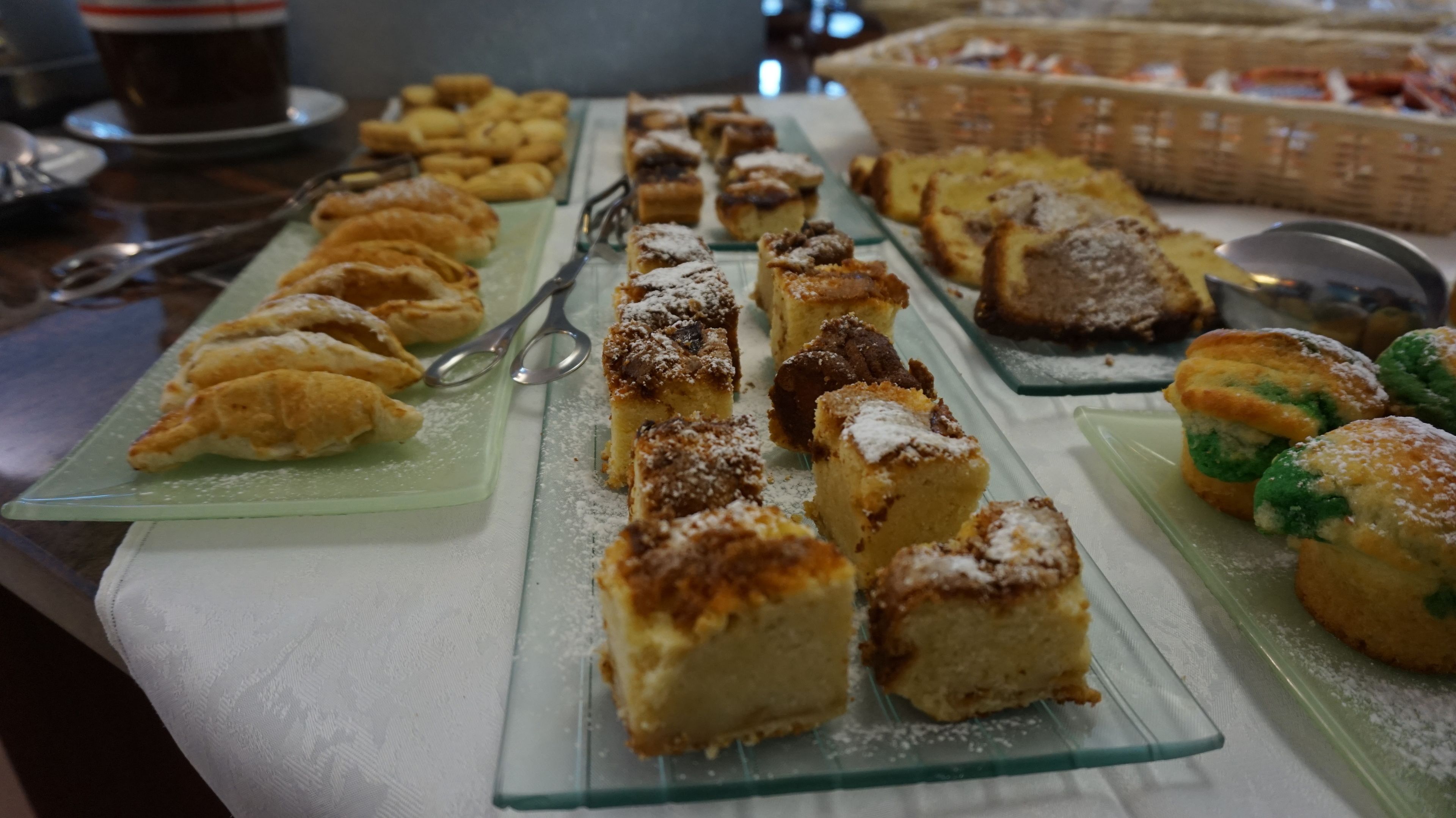 A buffet with various pastries and desserts on glass plates.