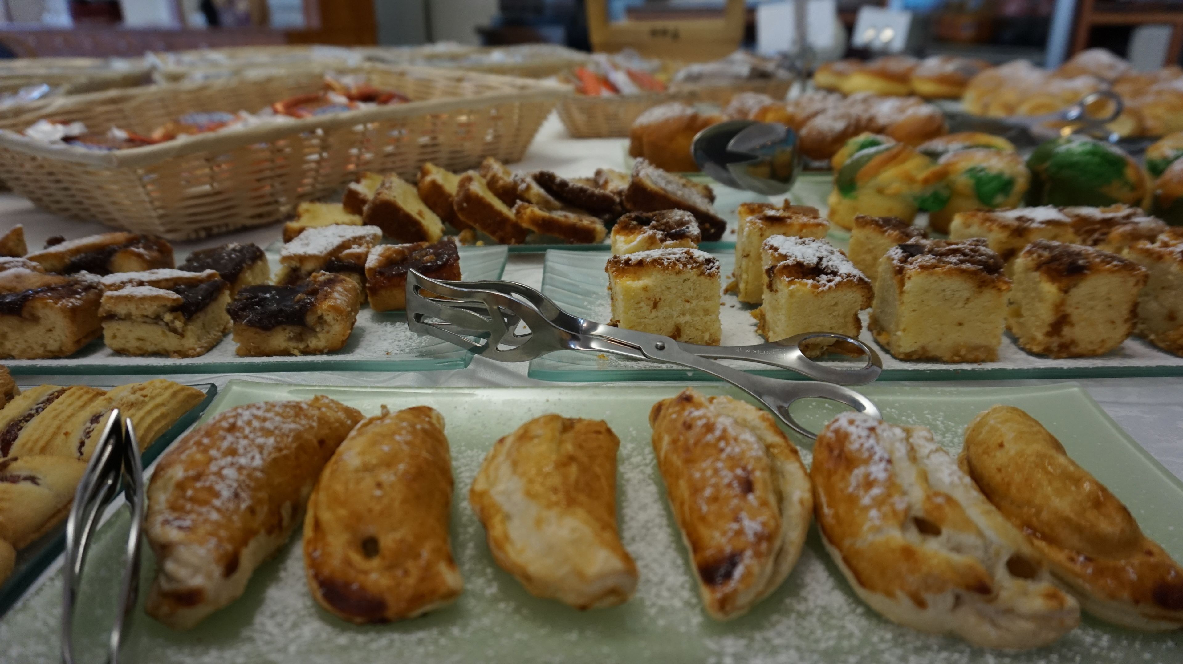A buffet with various pastries and desserts, including cakes and pastries, arranged on glass serving platters.