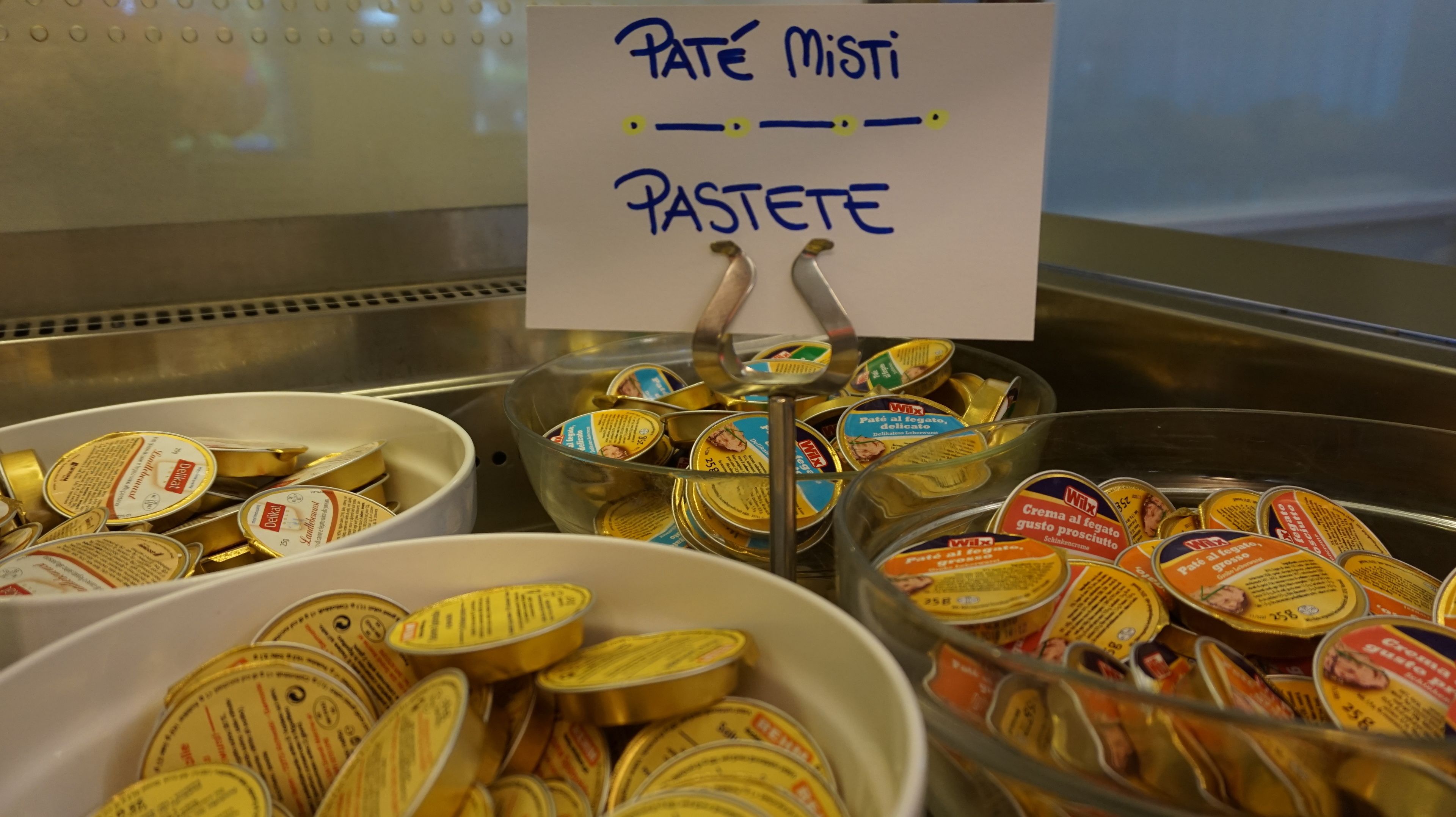 A buffet with labeled containers of pâté and pâté spreads.