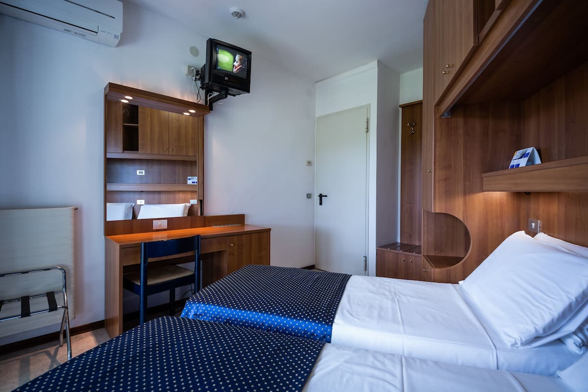 Een hotelkamer met een bed, bureau, stoel, televisie en een kledingkast.