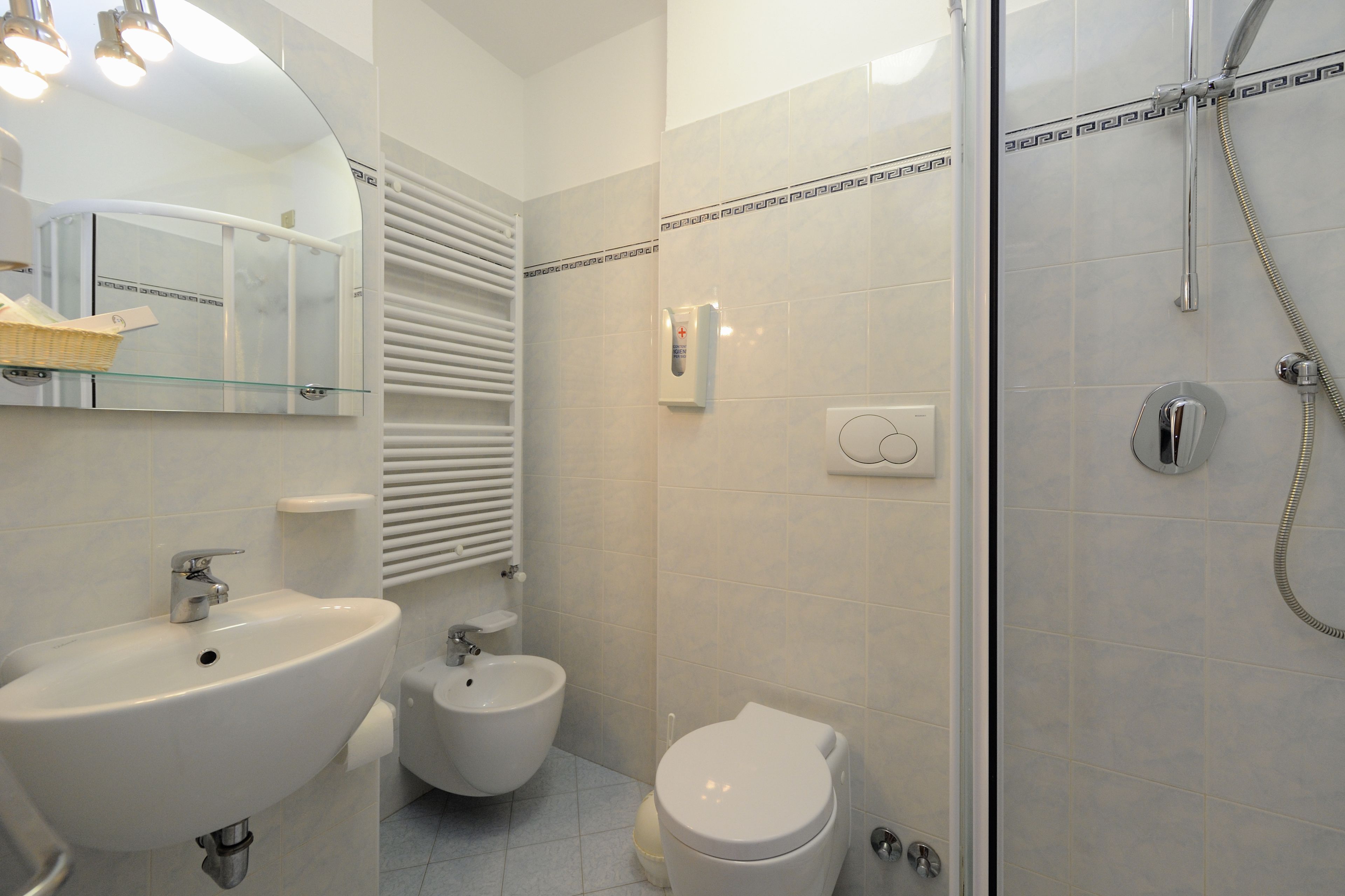 A modern bathroom with a sink, bidet, toilet, and a glass-enclosed shower area.