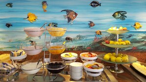 Un buffet proposant une variété de plats et une fresque représentant des poissons sur le mur.