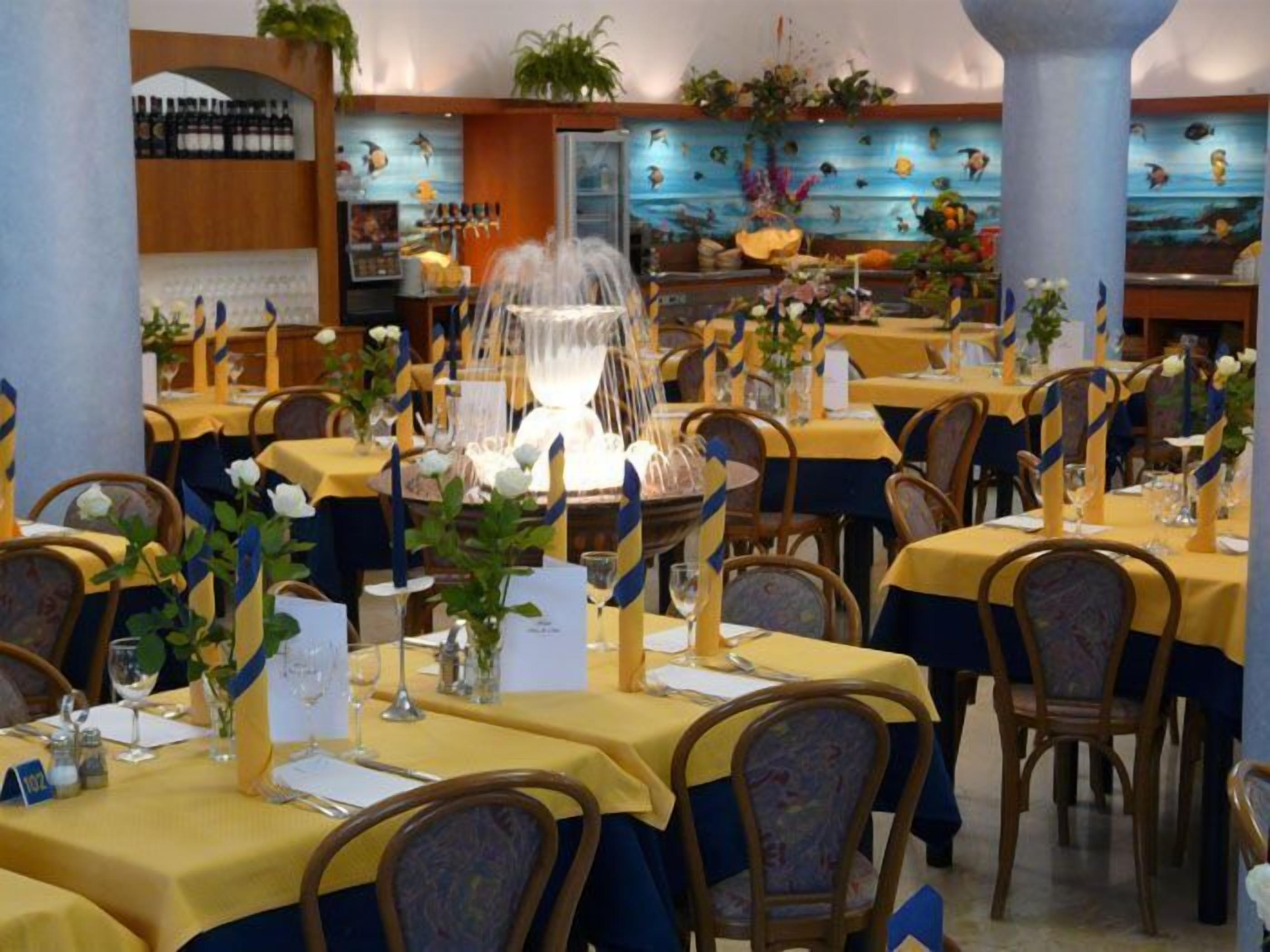 A restaurant with tables set for dining, featuring a central decorative fountain.