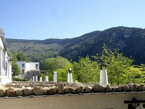 A coastal landscape with white buildings, a stone wall, and a hill in the background. - El Cercado Complejo Rural (Berchules)