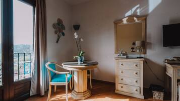 Una habitación con una mesa redonda, una silla, un tocador, un espejo y un televisor.