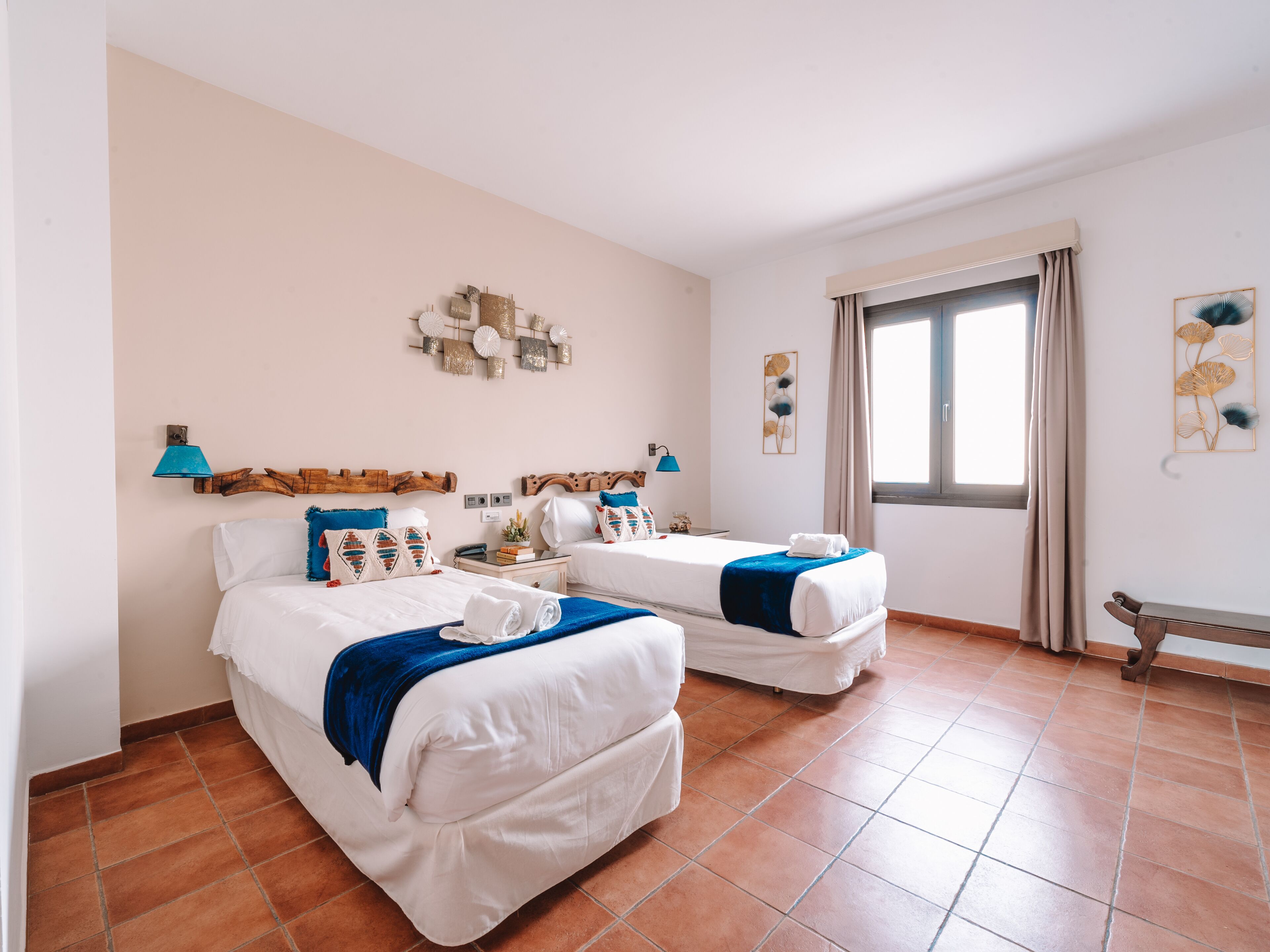 Une chambre d’hôtel avec deux lits, une grande fenêtre et vue sur la mer.