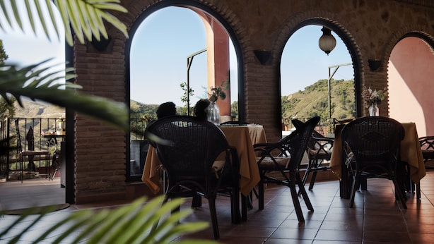 An outdoor patio with brick arches, wicker furniture, and a view of a hillside. - Hotel Boutique Cerro del Sol (Cenes de la Vega)