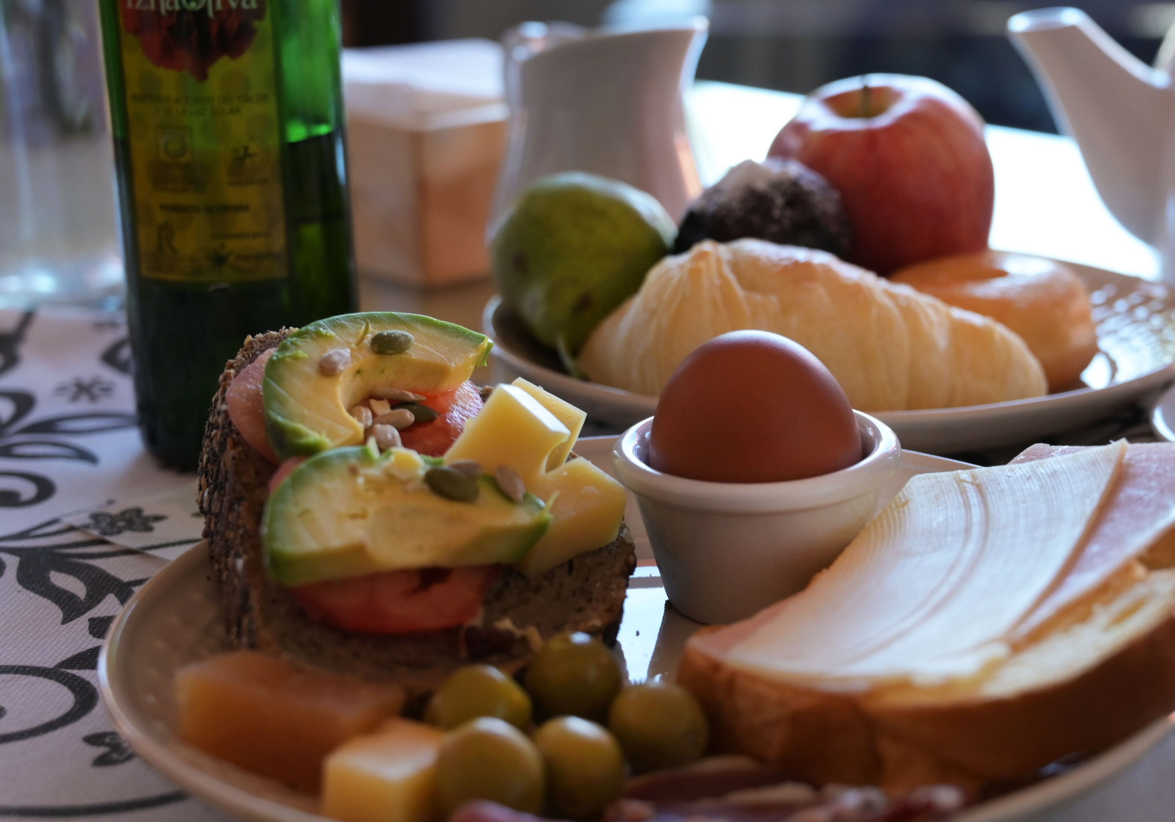 Une assiette contenant divers aliments, notamment du pain, du fromage, des tomates, des olives et un œuf dur.
