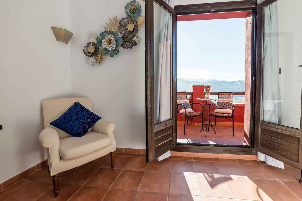 An open door leading to a balcony with a view of mountains.