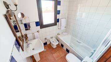A bathroom with a sink, toilet, bidet, and bathtub.