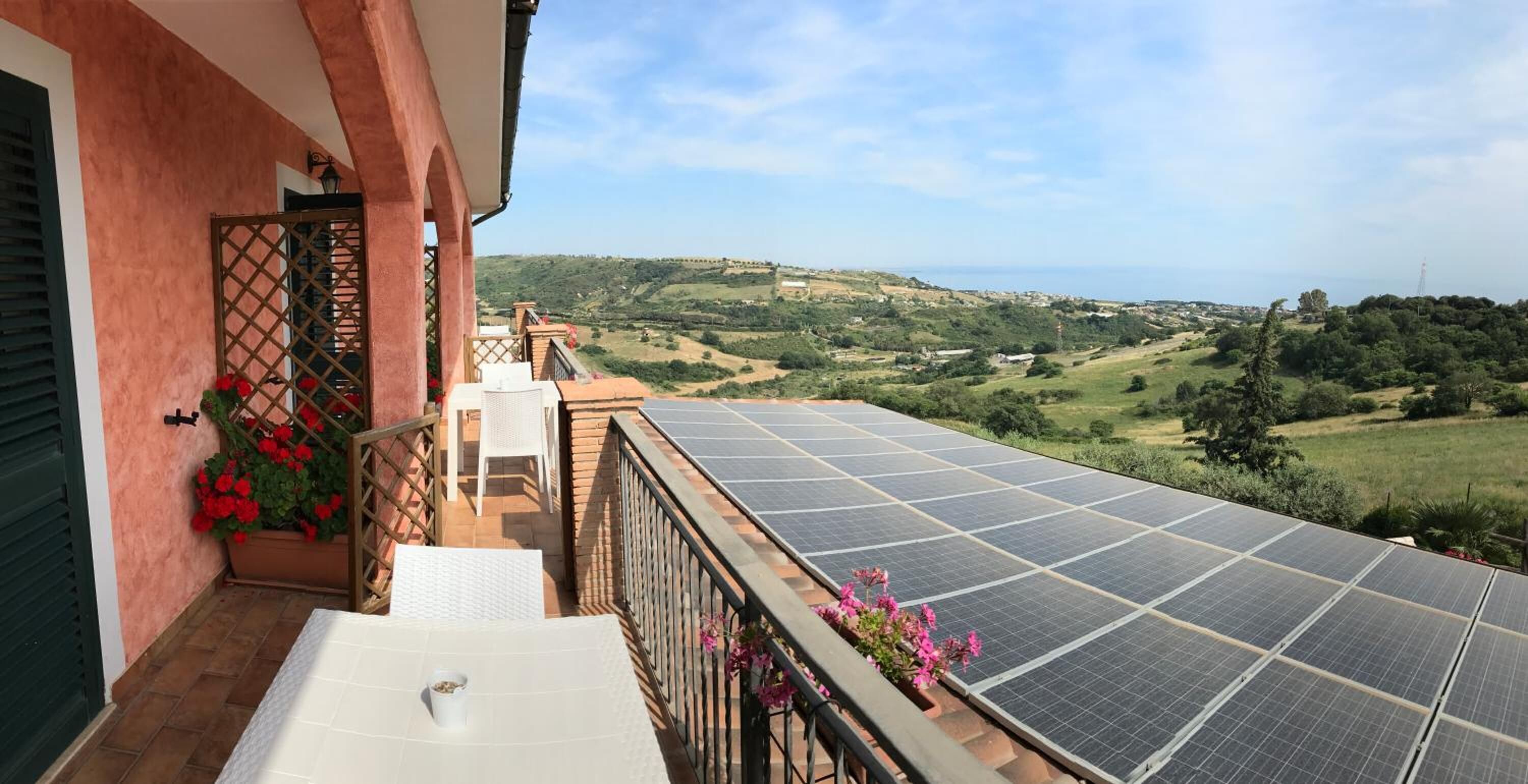 Un balcon équipé de panneaux solaires, avec une table, des chaises et des plantes en pot.