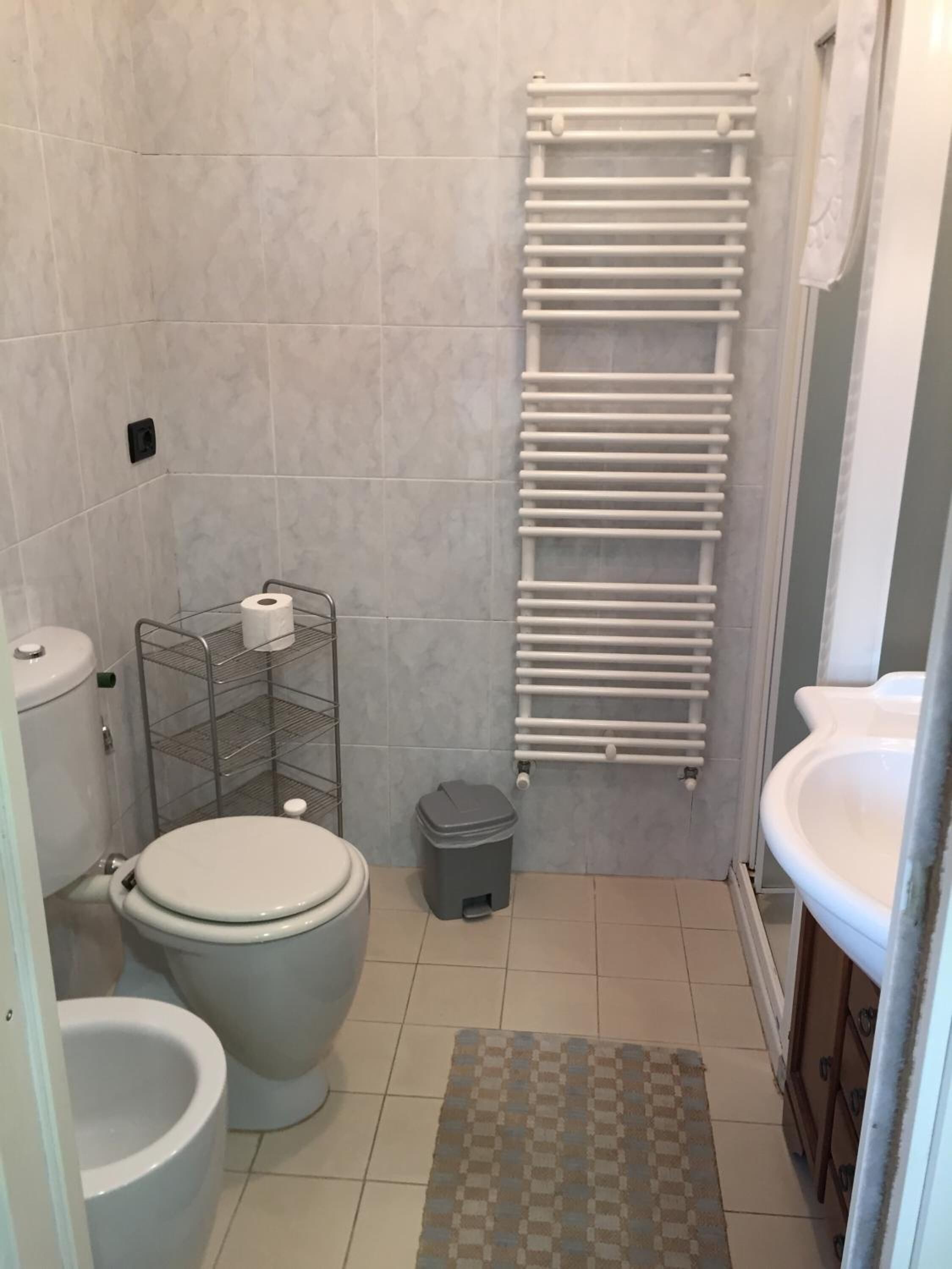 Une salle de bain équipée de toilettes, d’un bidet et d’un porte-serviettes.