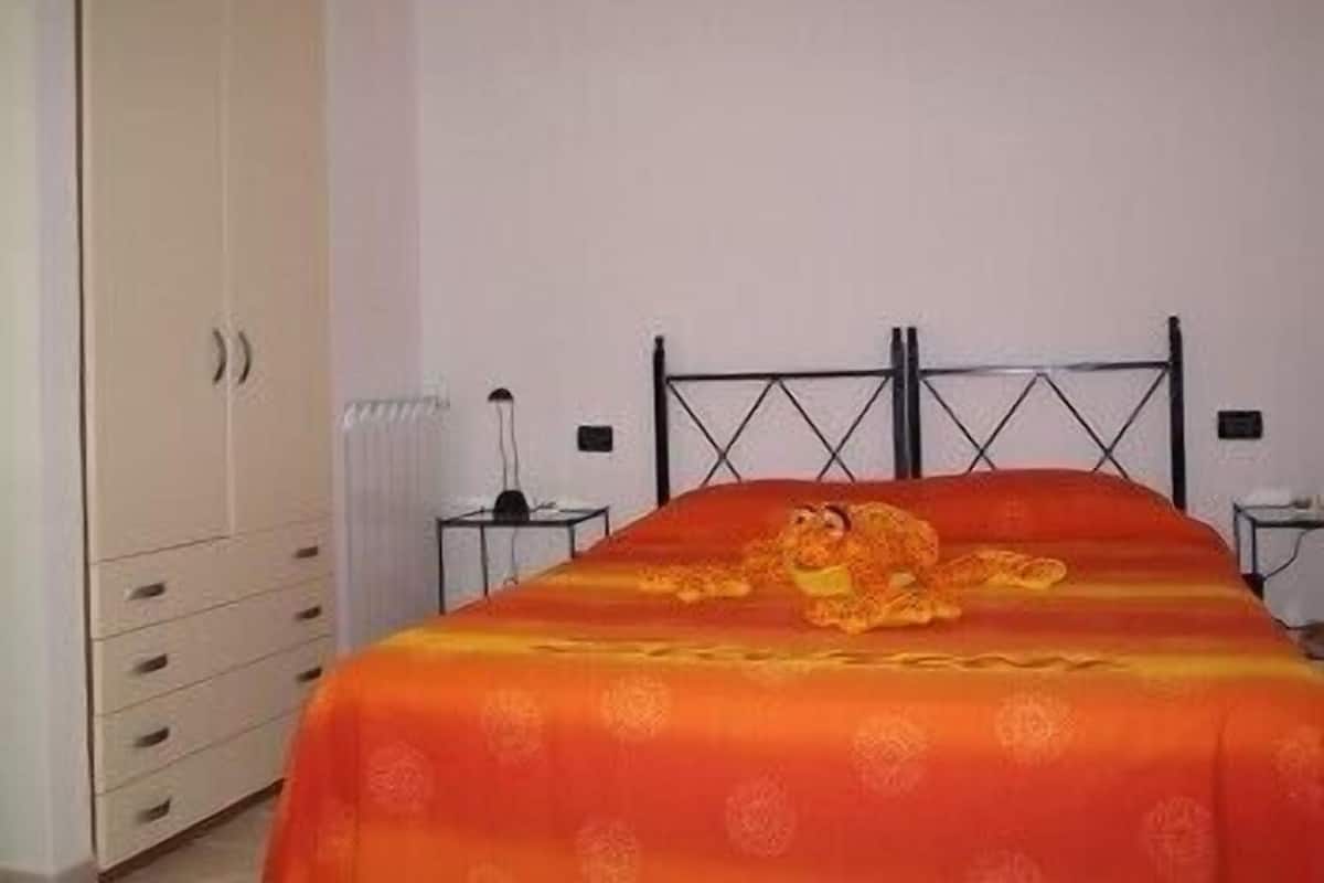 A bedroom with a bed, a wardrobe, and a nightstand.