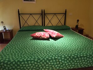 A bed with a green floral bedspread and two red pillows. - Elicrim (Santo Stefano di Magra)