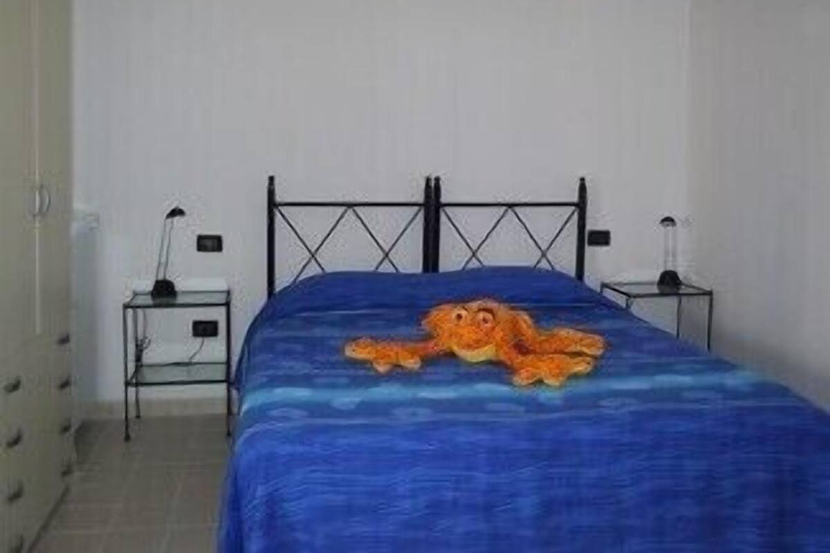 A bedroom with a bed, two bedside tables, and a wall-mounted lamp.