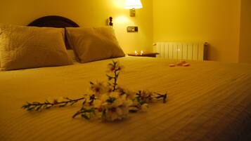 Una cama bien hecha con almohadas, una mesita de noche con una lámpara y una decoración floral en la cama.