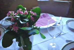 Una mesa dispuesta con una copa de cristal transparente, un plato blanco y una servilleta morada.