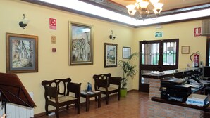 A reception area with a brick counter, wooden chairs, and a potted plant. - La Encina Centenaria (Monachil)
