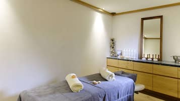A spa room with a bed, a wooden cabinet, and a mirror.