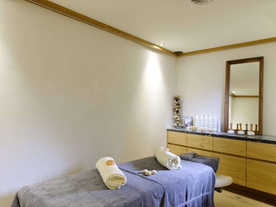A spa room with a bed, a wooden cabinet, and a mirror.
