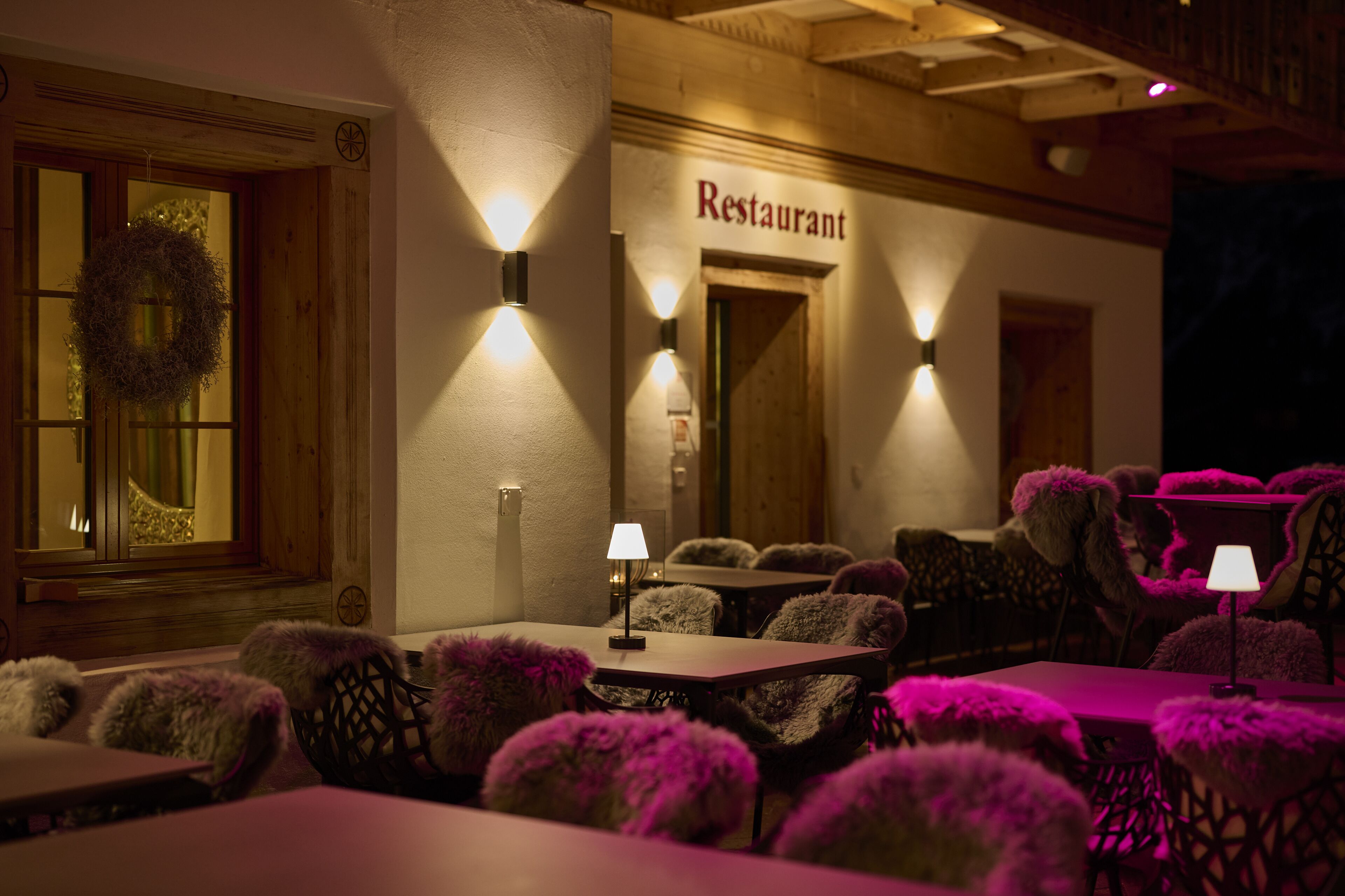 A restaurant interior with wooden walls, a sign reading "Restaurant," and tables with fluffy chairs.