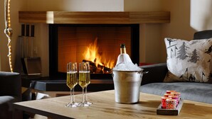 A cozy living room with a fireplace, a table with glasses of champagne, and a bucket of ice.