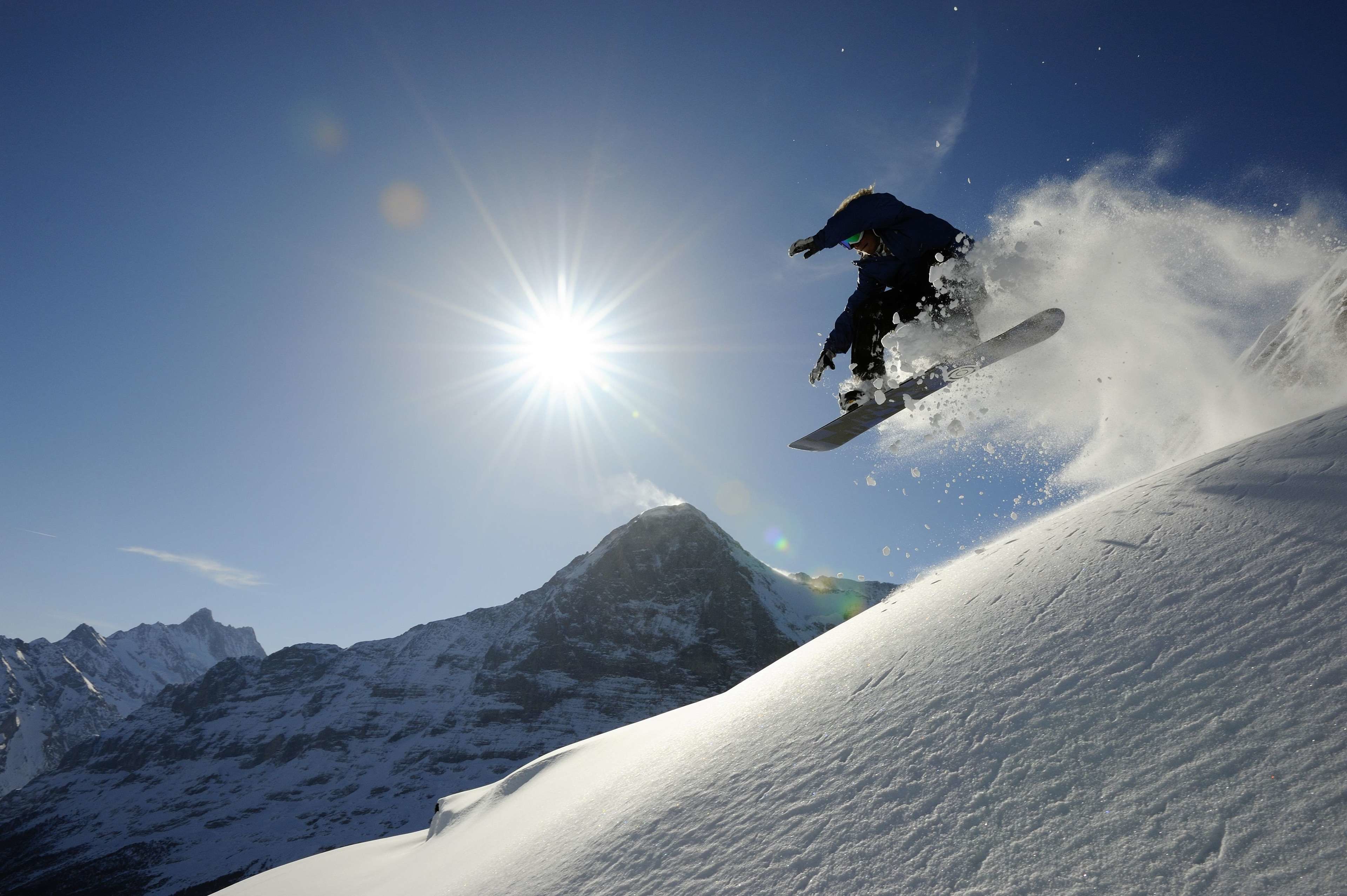 Un snowboarder en pleno vuelo sobre una ladera nevada de montaña.