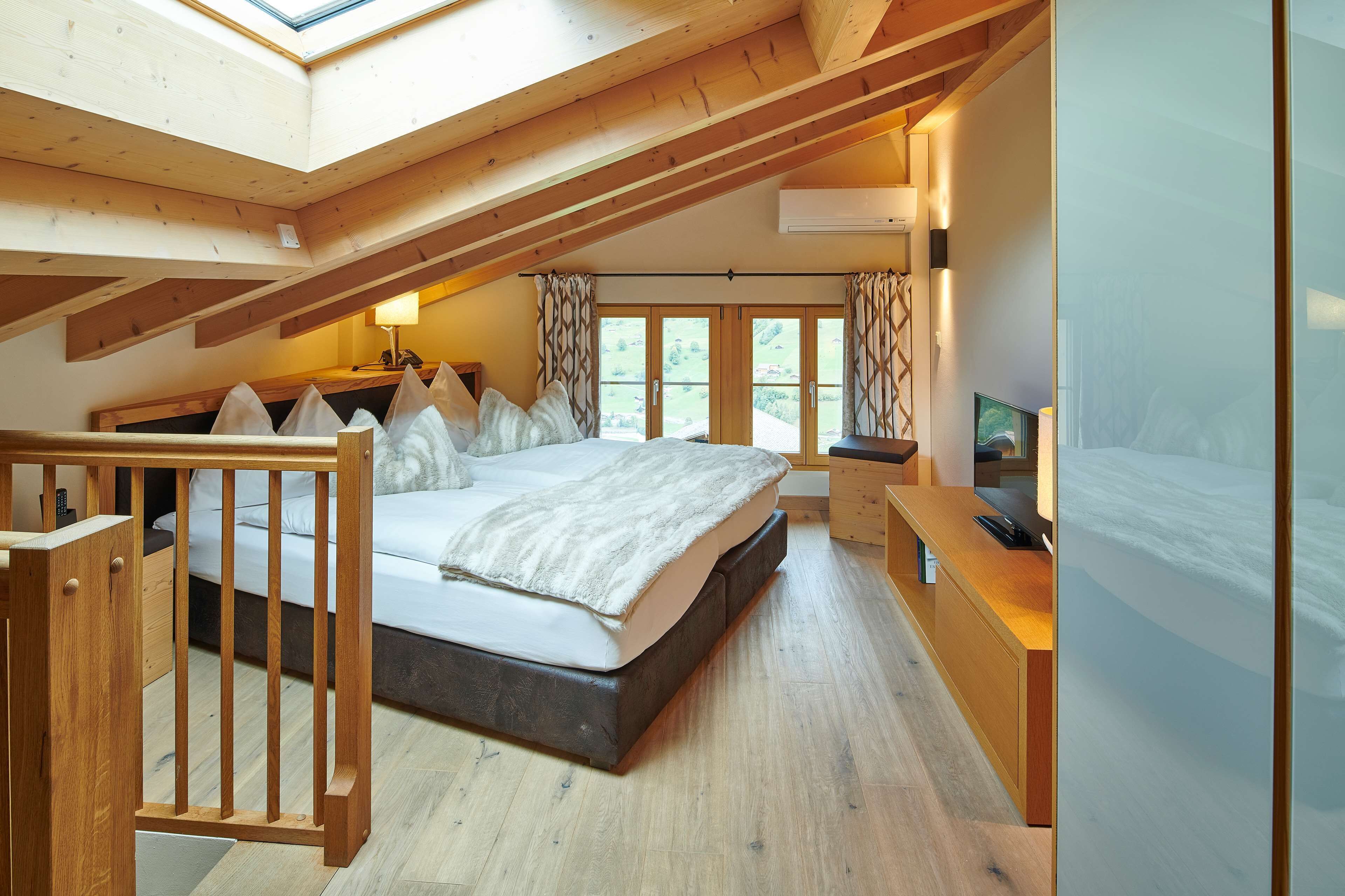 Un dormitorio con techo inclinado, una cama, un escritorio y un televisor.