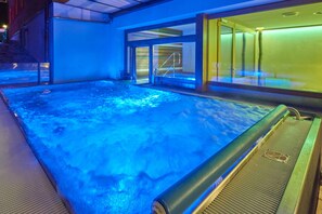 A heated outdoor pool area with a glass enclosure and a metal deck.