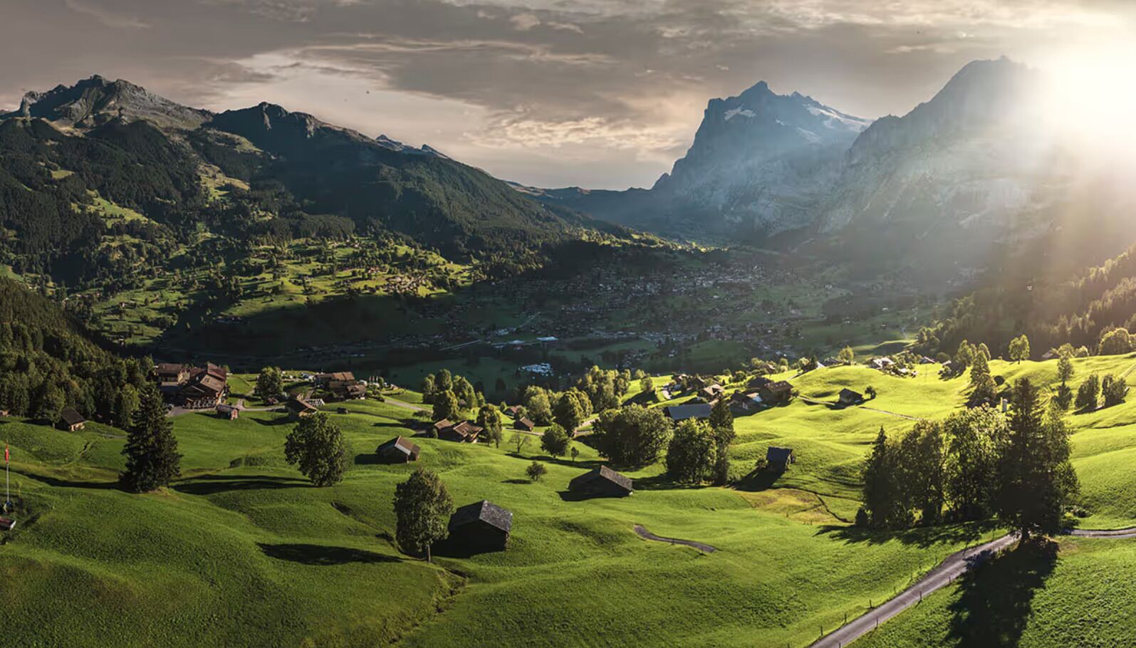 Un paisaje montañoso con un pequeño pueblo, casas y una carretera.