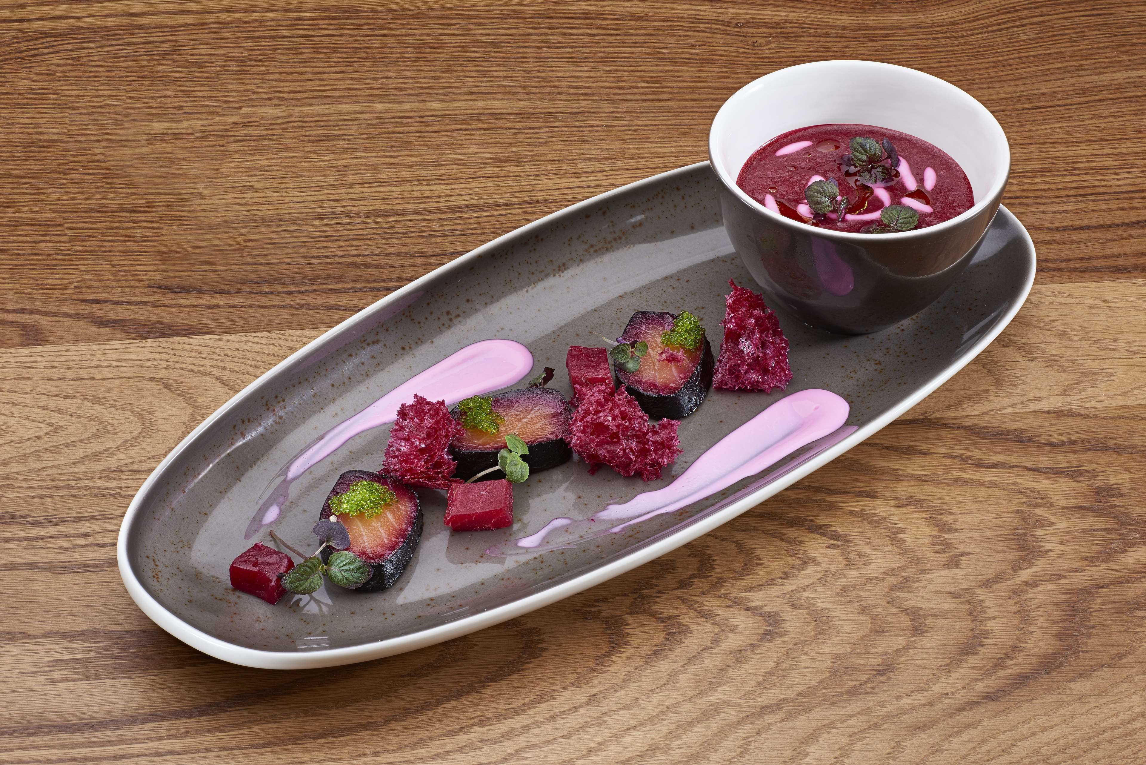 A plate of food with a bowl of soup on a wooden table.