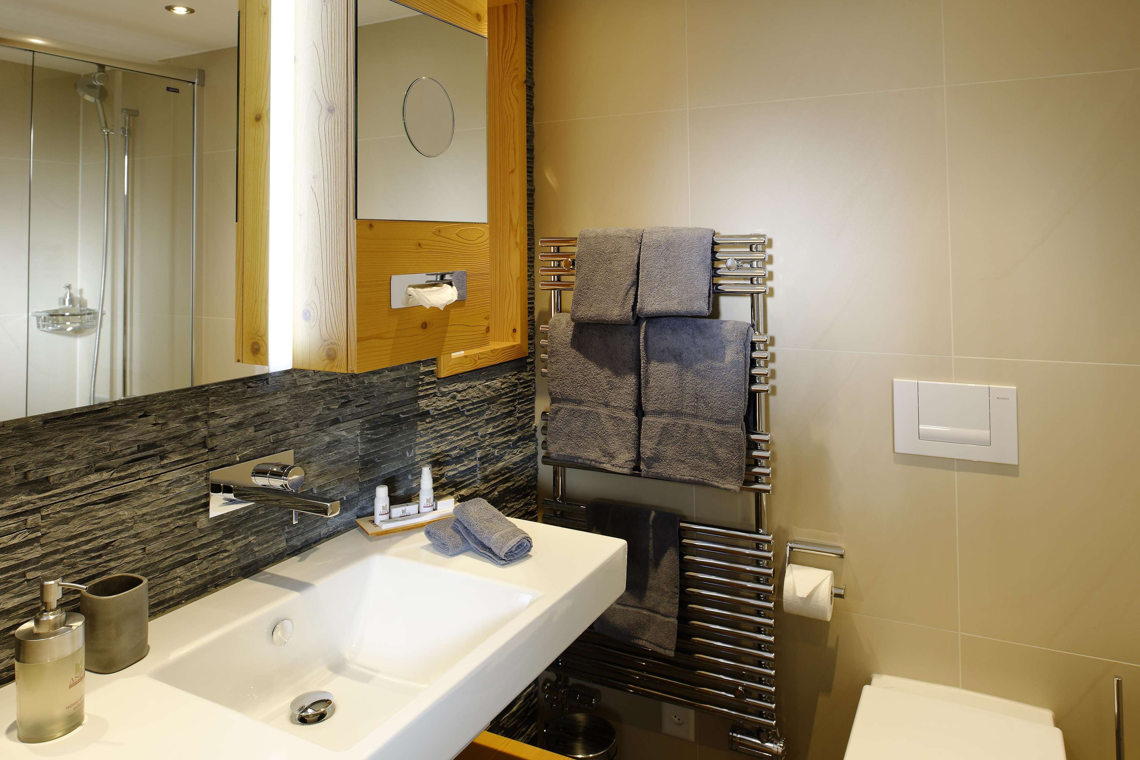 Une salle de bain moderne avec un grand lavabo, un miroir, un porte-serviettes et un espace douche.