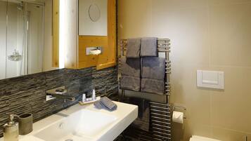 Une salle de bain moderne avec un grand lavabo, un miroir, un porte-serviettes et un espace douche.
