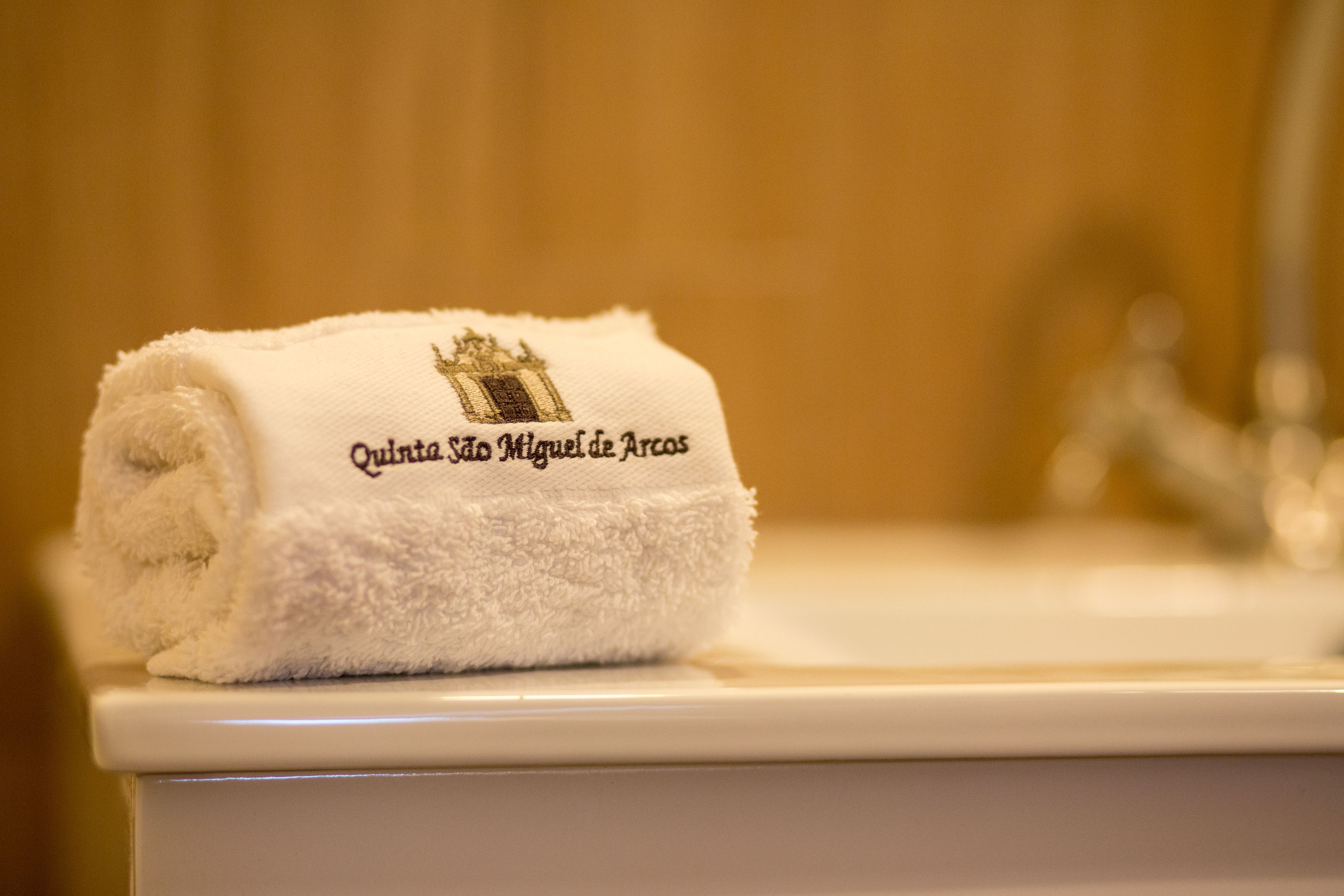 A white towel with embroidered text on a white toilet.