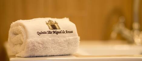 A white towel with embroidered text on a white toilet.