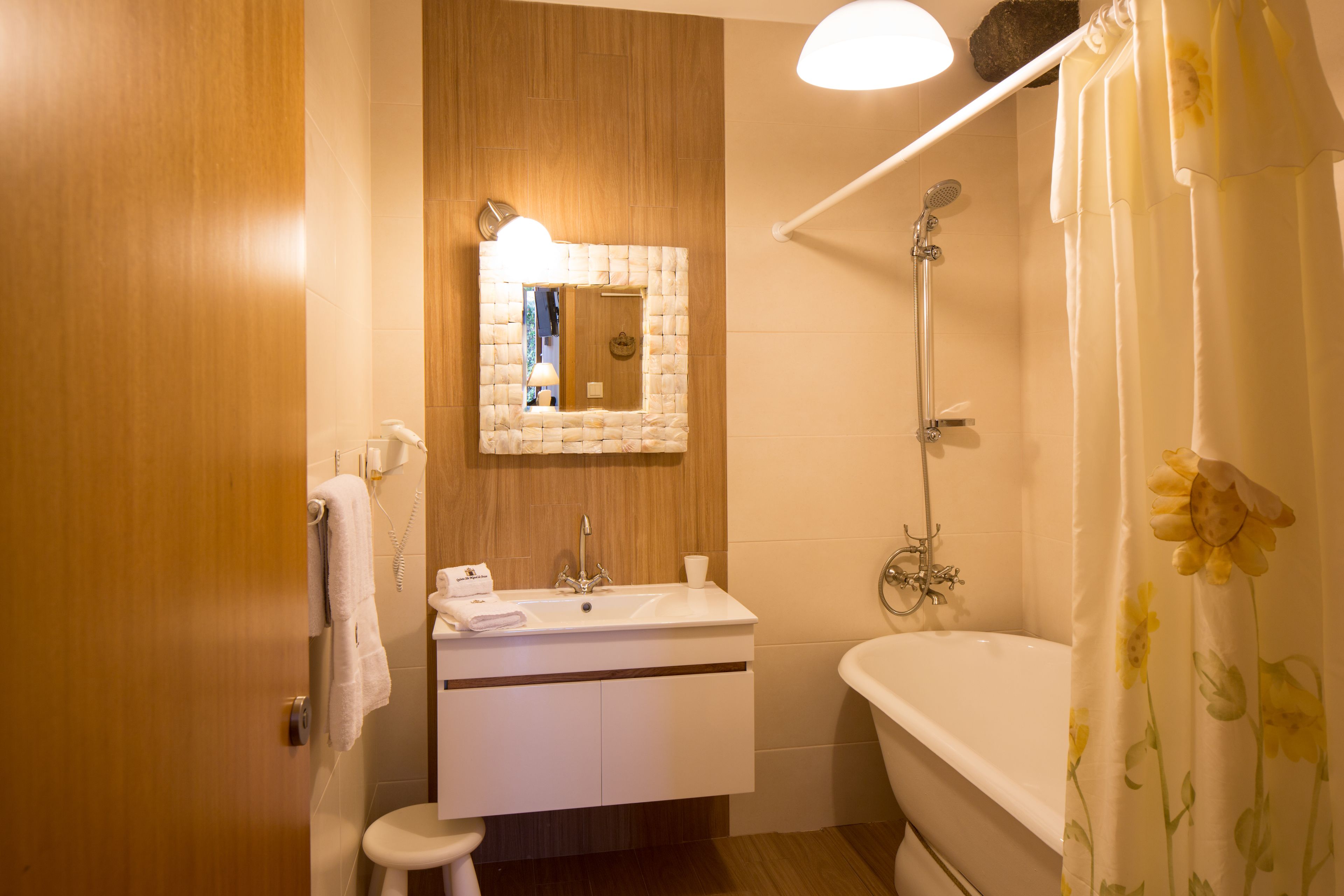 A bathroom with a wooden vanity, a sink, a mirror, a shower, and a toilet.
