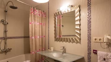 A bathroom with a shower, a sink, a mirror, and a towel rack.