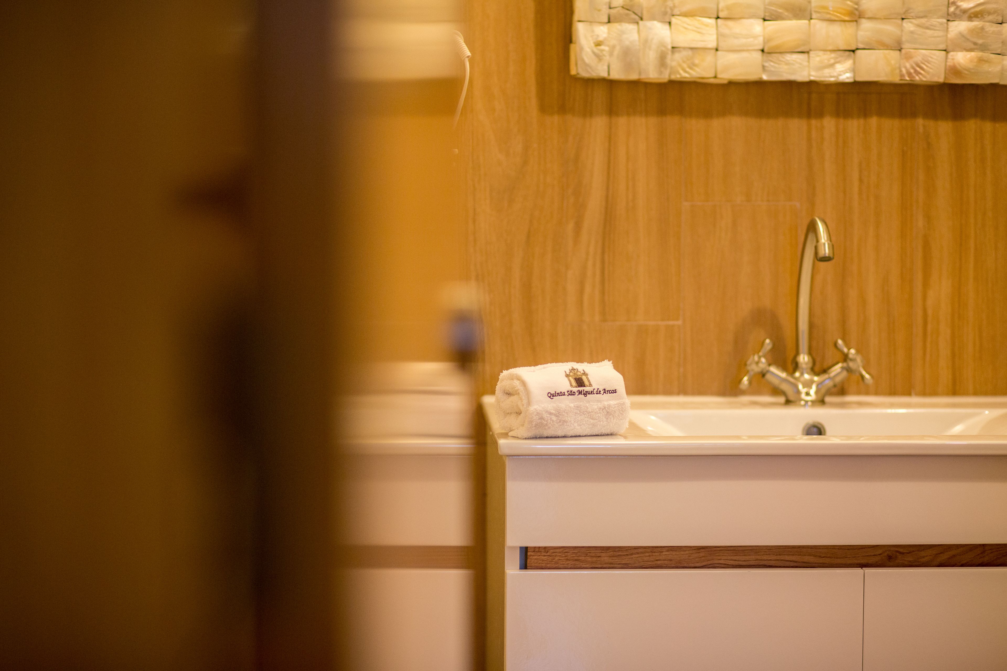 A bathroom with a wooden vanity, a white sink, and a towel with a logo.