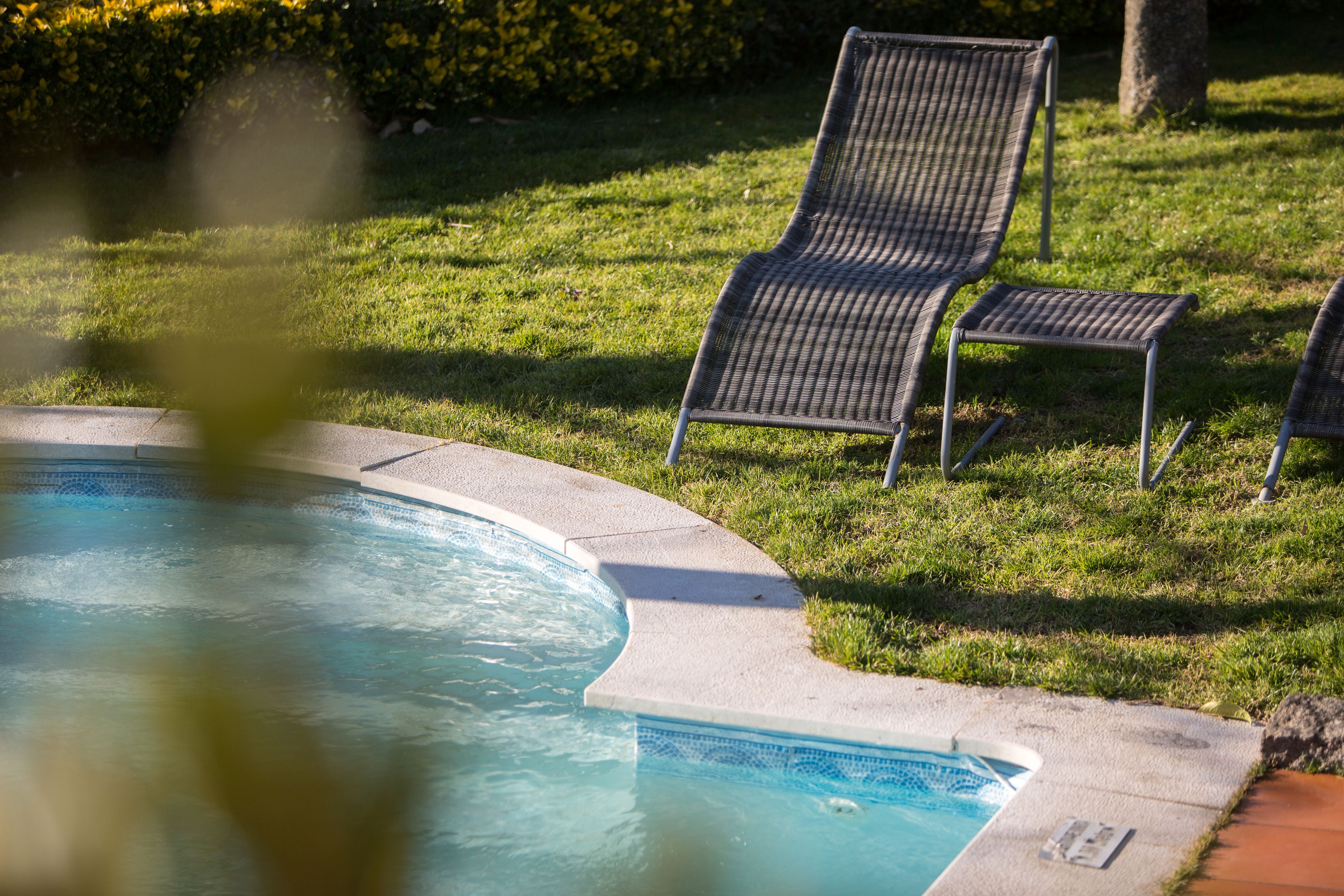 Una piscina con dos sillas de descanso y un borde con baldosas.