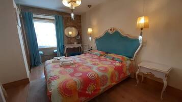 A bedroom with a bed, two bedside lamps, a dresser, a mirror, and a window with curtains.