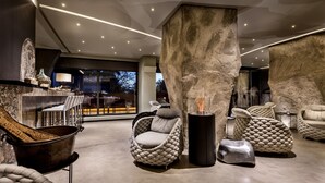 A modern interior with a stone column, cushioned seating, and a large window overlooking a cityscape. - Vitória Stone Hotel (Évora)
