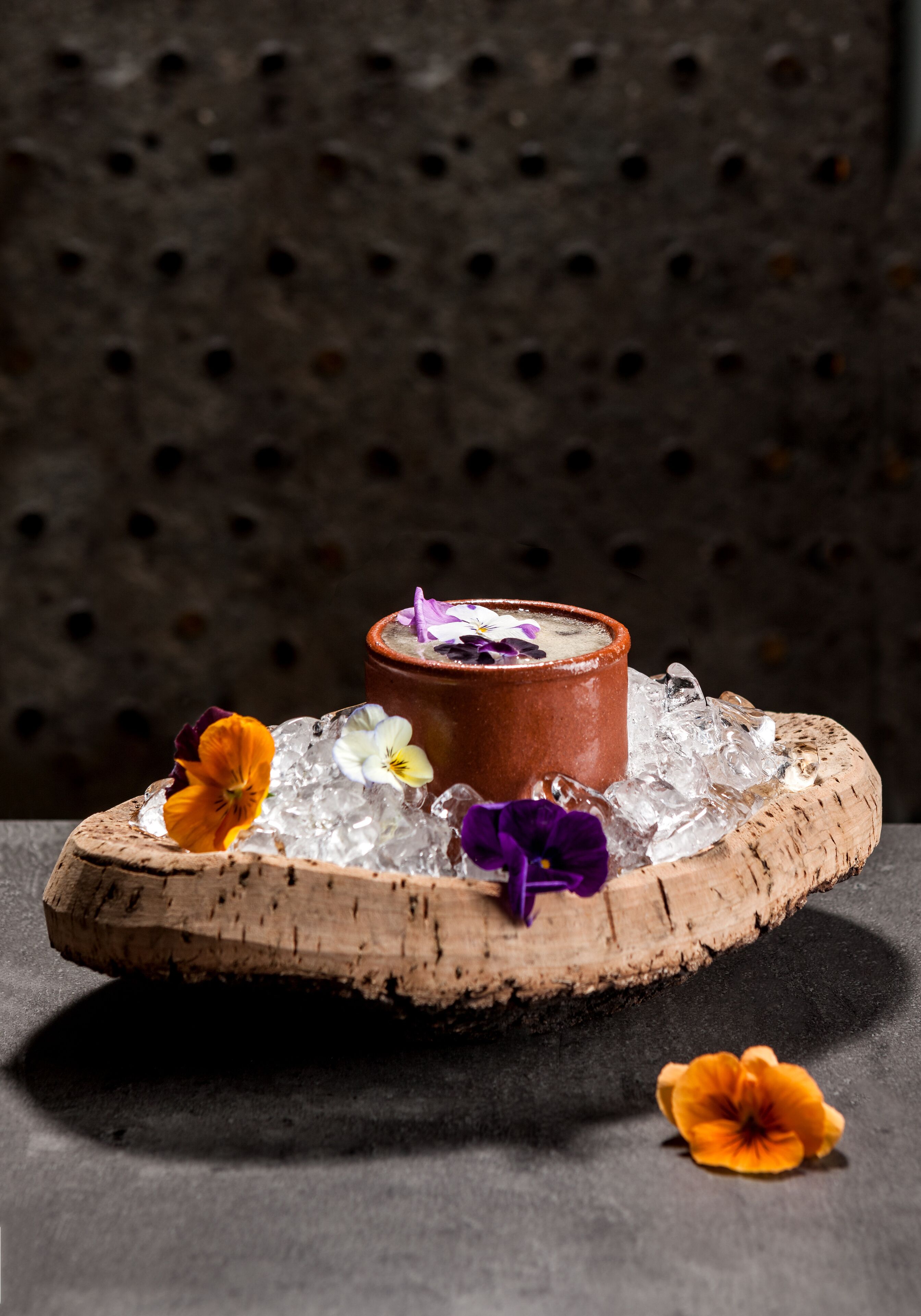 Un postre sobre una tabla de madera, con hielo y flores.